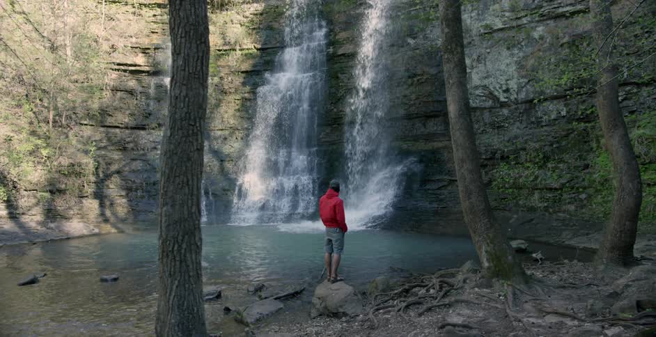Man standing at the basin of some waterfalls