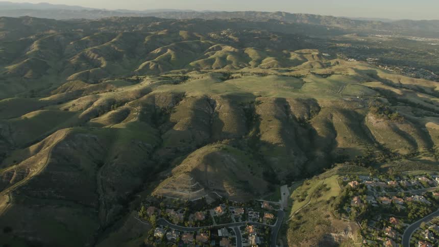 Aerial view of  grass covered mountains with a  small village in the foreground
