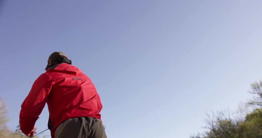 A man is casting a line from a fishing pole on a sunny day