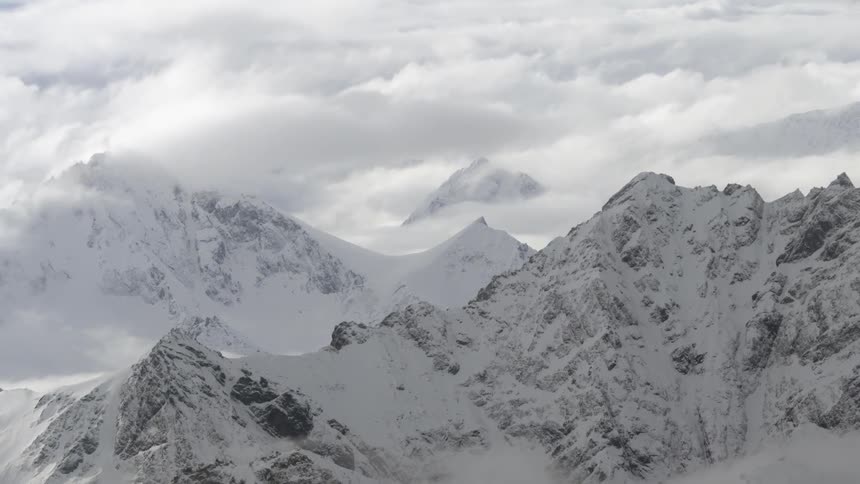 Tall snow covered mountains above the clouds
