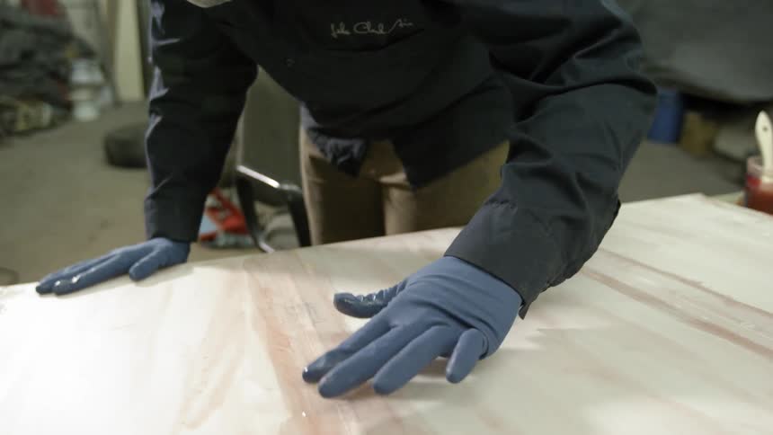 A woman wearing a respirator mask and gloves makes repairs