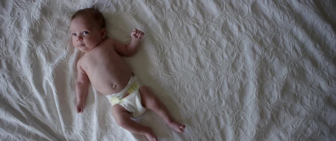 An infant lays on a blanket