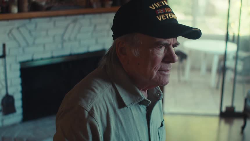 An old veteran squeezes a tiny plastic american flag as he looks very upset