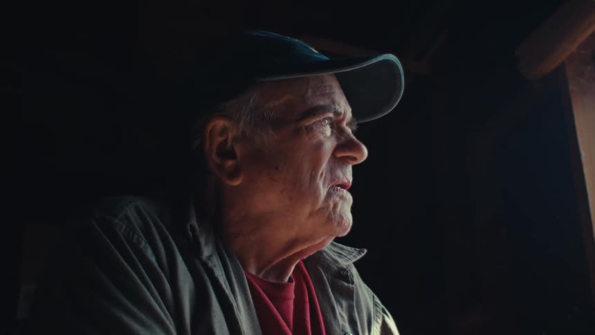 An old man indoors suddenly looks distraught