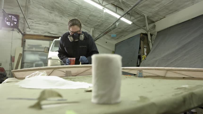 A woman with a face mask works in a garage