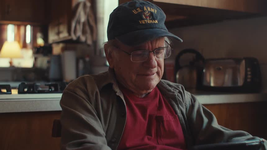 Emotional elderly man sitting at the table using a tablet
