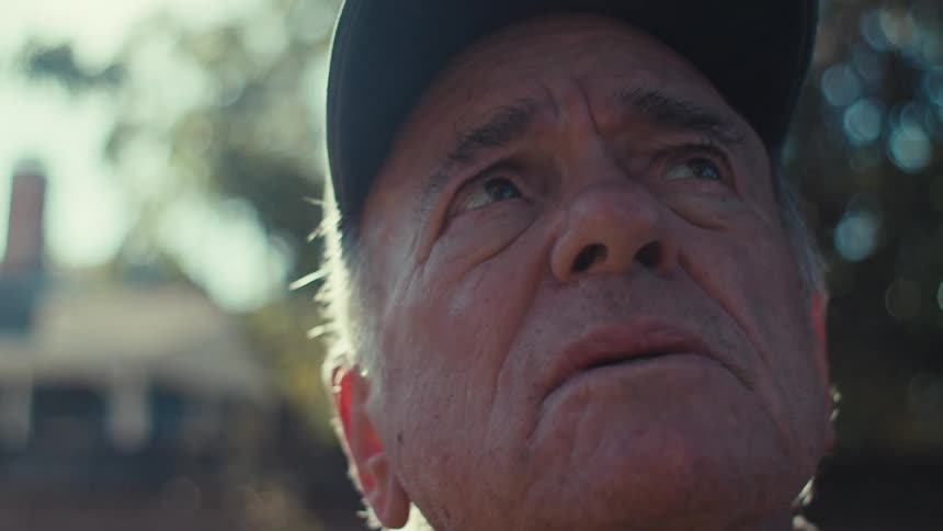 Portrait of an elderly man in a backyard looking up