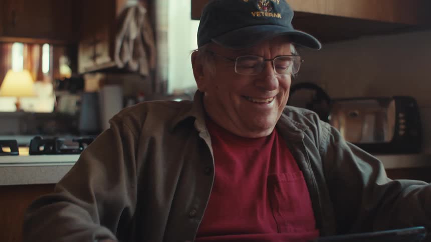 An image of an elderly man laughing very hard indoor