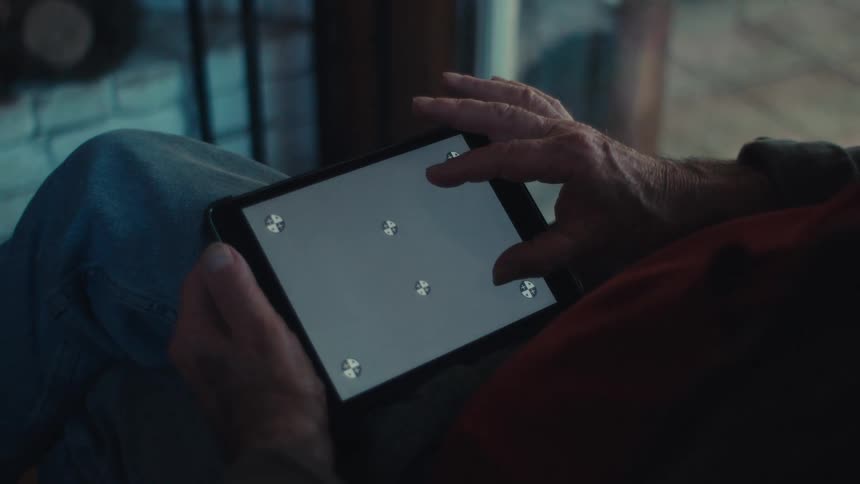 Elderly man sits at home using a tablet