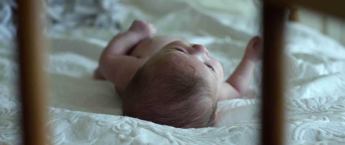An infant lays on a bed