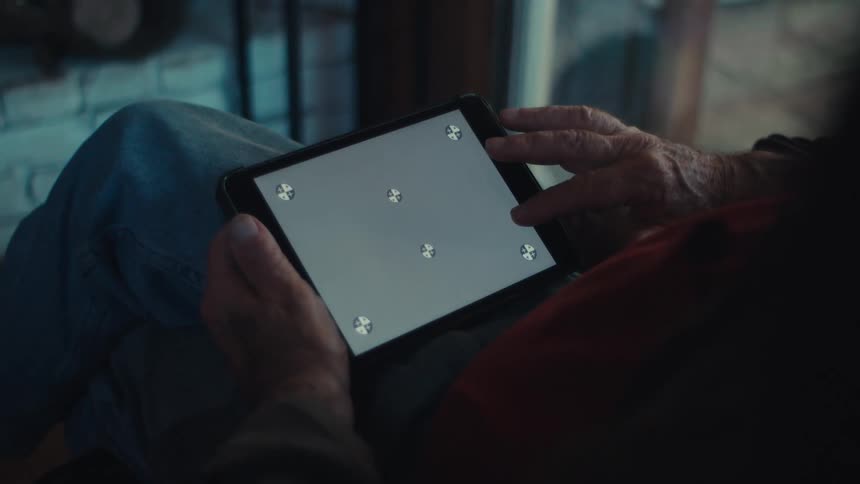 An old man attempts to scroll a tablet screen that isnt working correctly