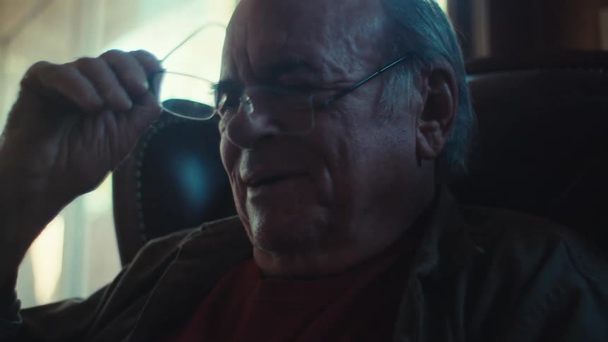 Portrait of an elderly man interacting with a cell phone and taking off his glasses