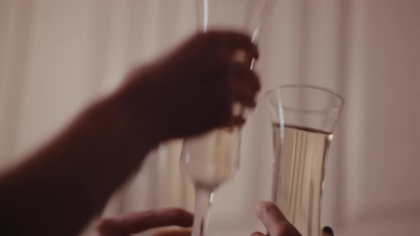Three people clink champagne flutes together as a cheers in a home