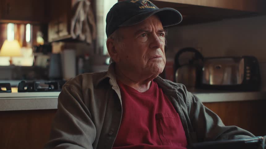 Elderly veteran takes notes while using a tablet then stops to think