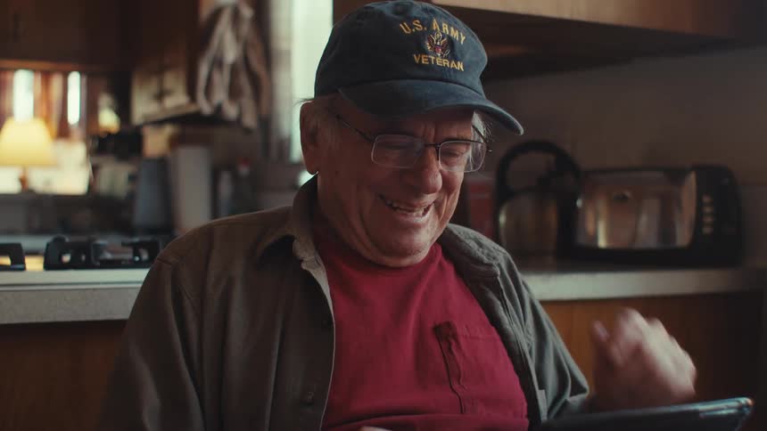 A man laughs and claps at his laptop