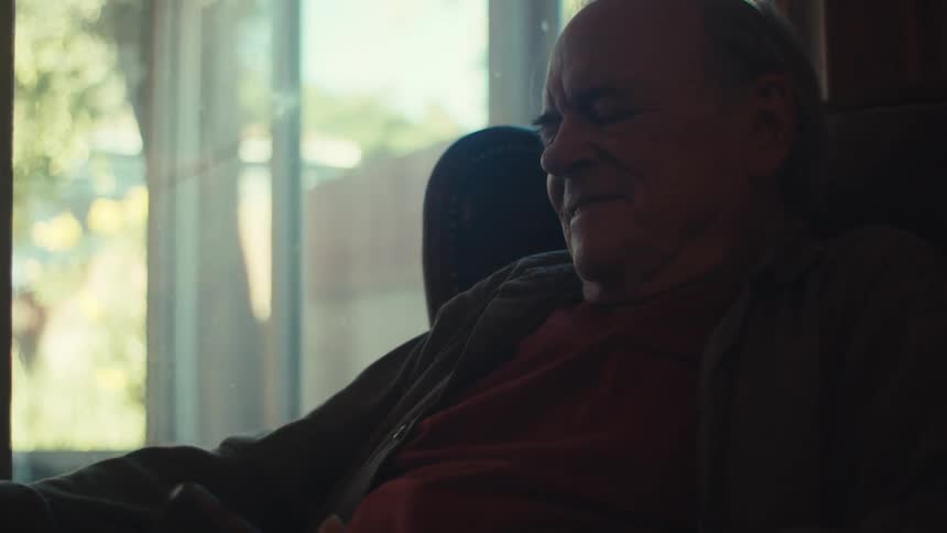 Smiling elderly man puts his eyeglasses on before viewing his smartphone