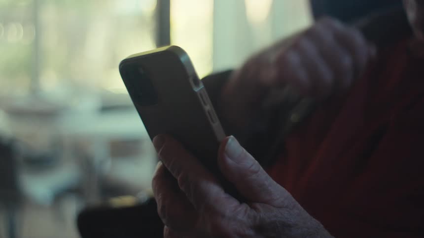 Elderly man smiles and gestures during a video call on his smartphone while at home