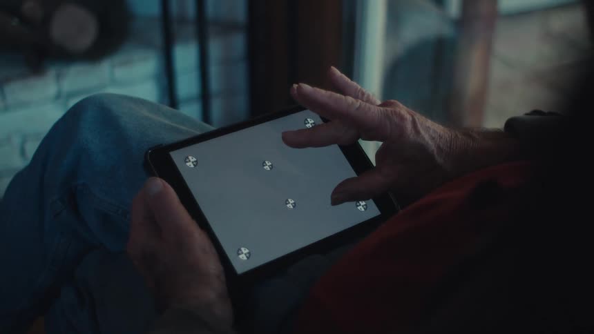 Elderly man sits at home and uses a tablet