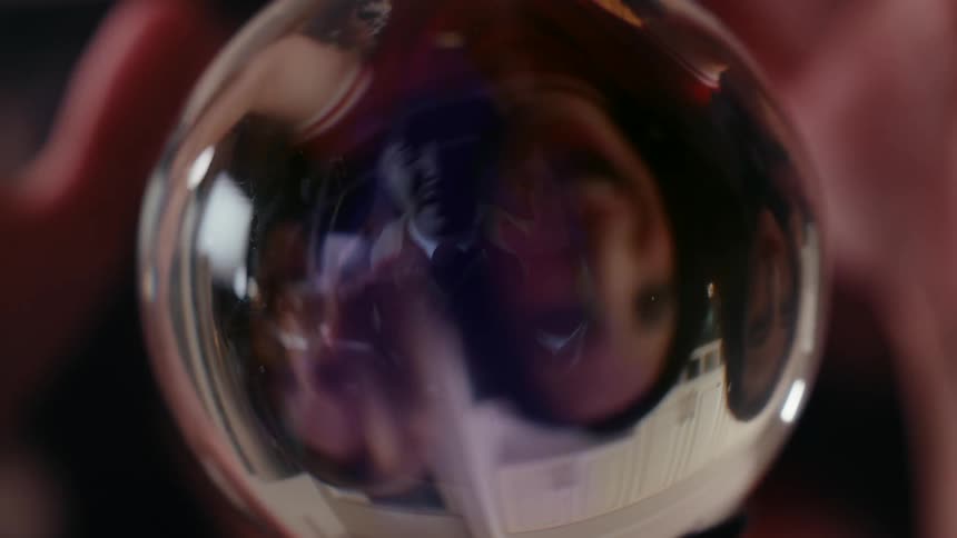 Three women look at a fearful man in a crystal ball