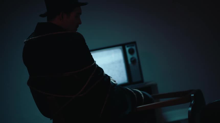 A man is tied up in front of a television set