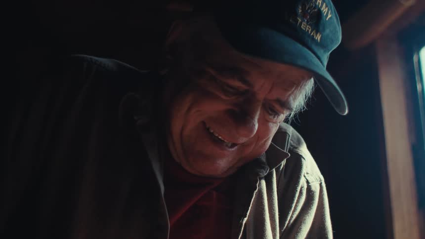A man smiles as he happily saws away in a workshop