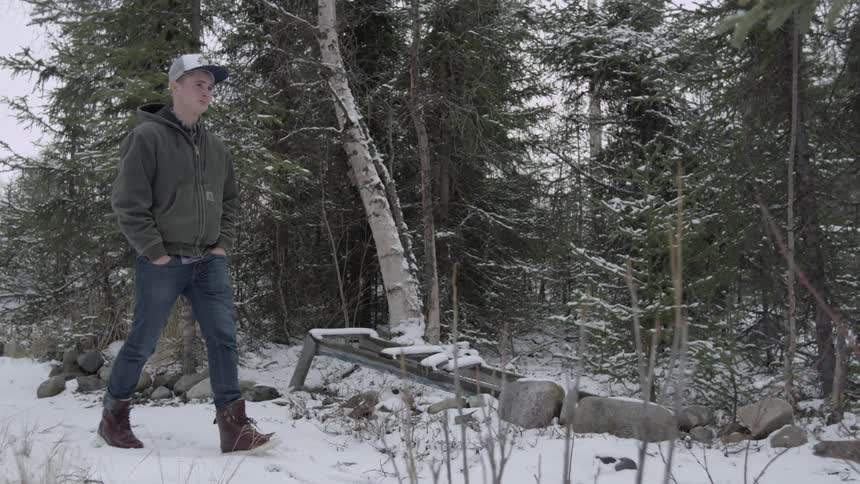 A young man is walking in the snowy woods
