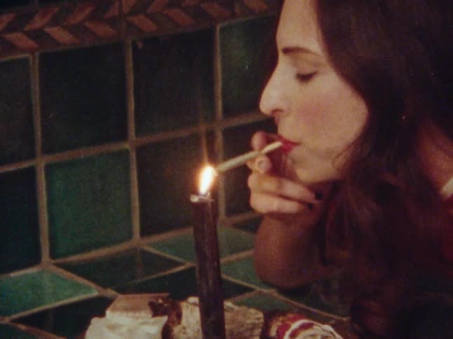 Woman lights a cigarette from a tall candle