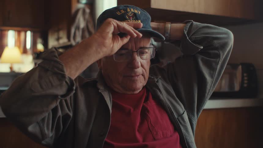 An image of an elderly man putting on a cap
