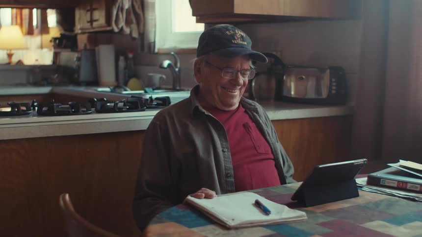 A man laughs while looking at his tablet
