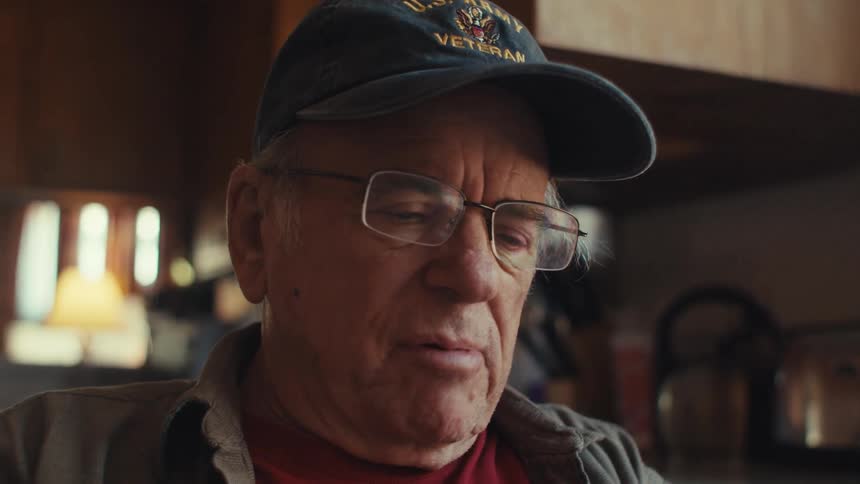 Portrait of an elderly man in a cap and glasses sitting and talking