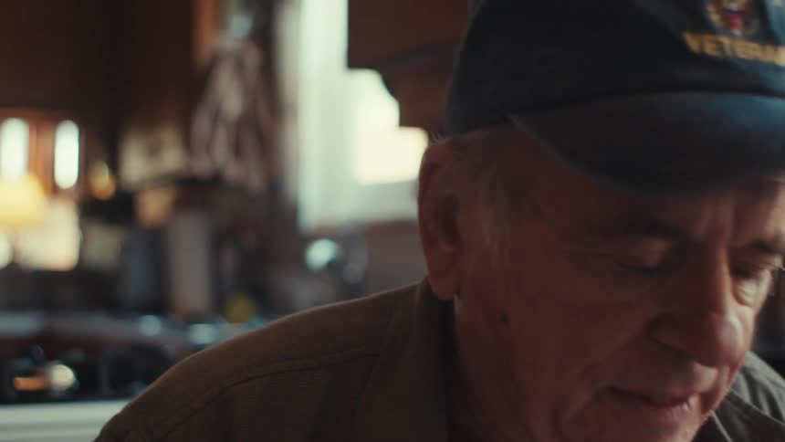Portrait of a seated elderly man putting on glasses