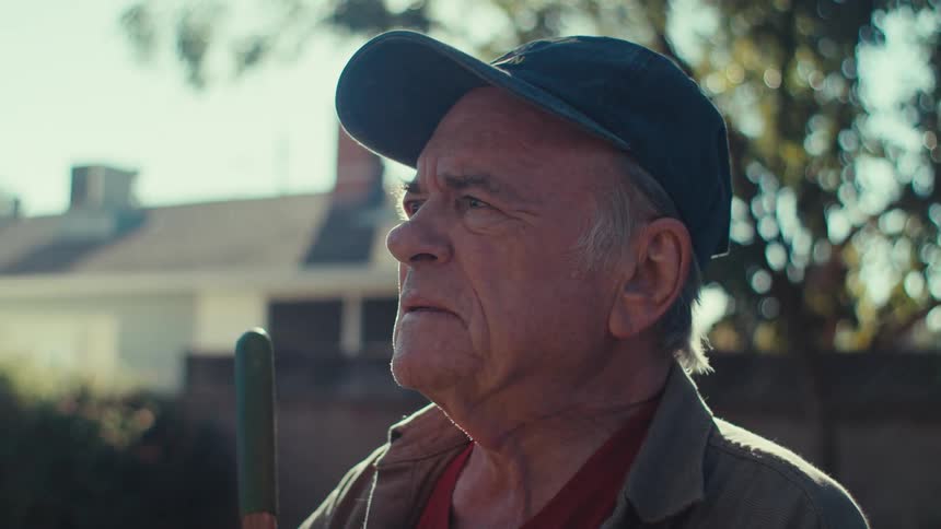 Elderly man cleaning the yard and looking thoughtful