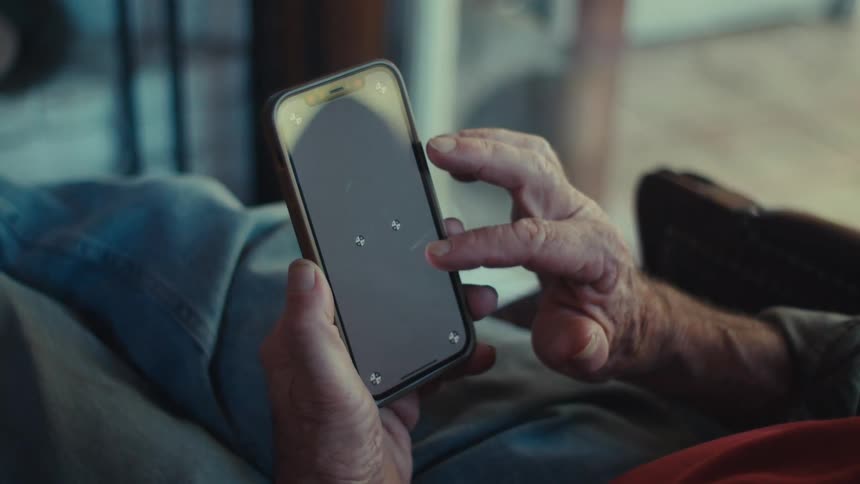 Hands of an elderly person touching the screen of a smartphone
