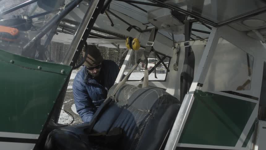 Man adjusting things on a small plane on a cold day