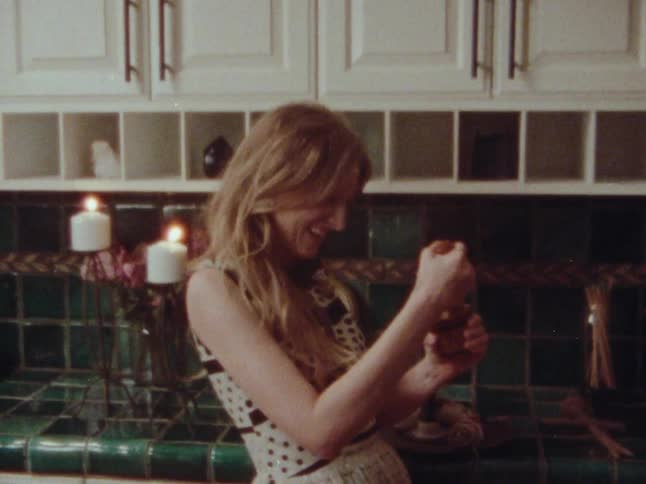Two cheerful women in the kitchen one holding a drink