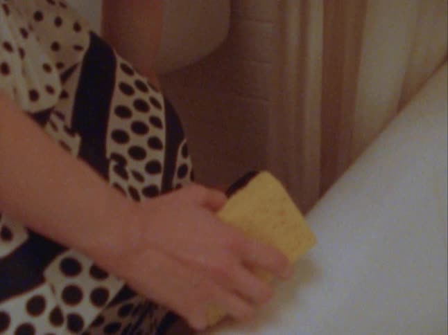 Womans hands holding a sponge and passing it towards a bathtub
