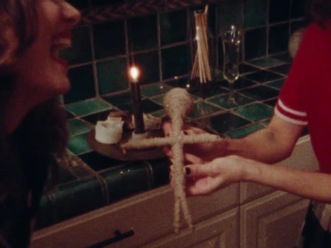Three happy women in the kitchen having fun with a voodoo doll