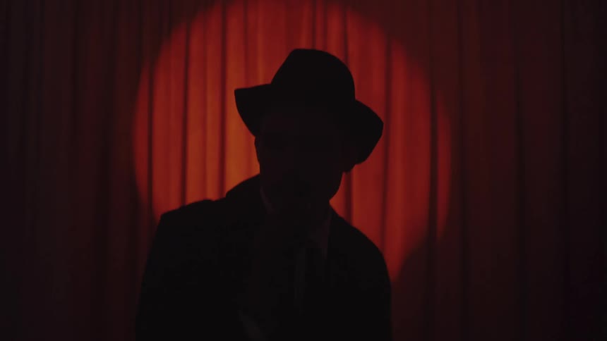 Silhouette of a man in a hat against curtain