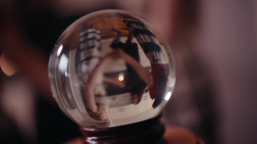 Close up of a small glass globe reflecting three women holding hands creating