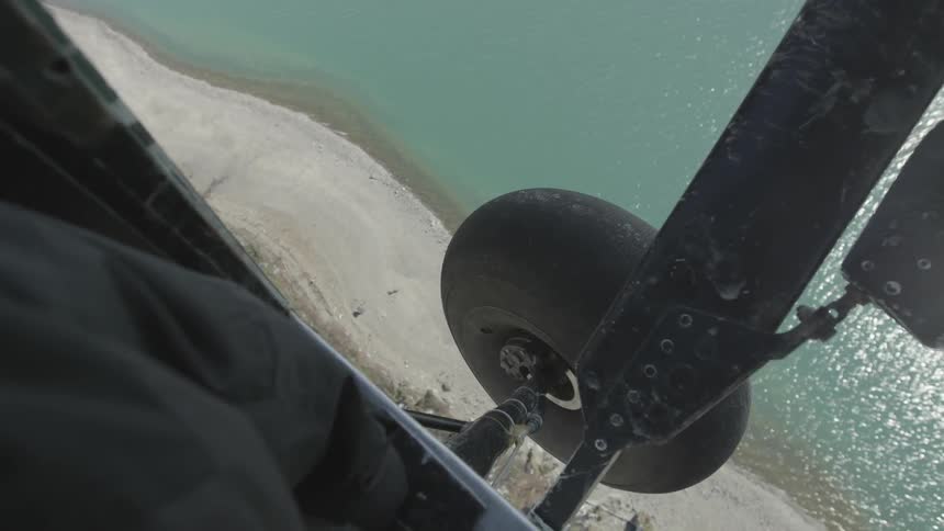 Aerial view looking out of an airplane down at a beach and ocean