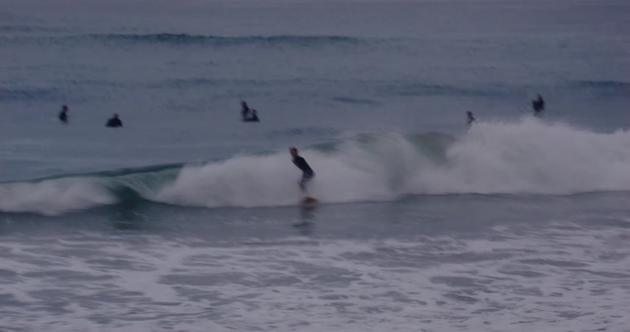 Surfers in the sea with one of them doing a maneuver on a wave
