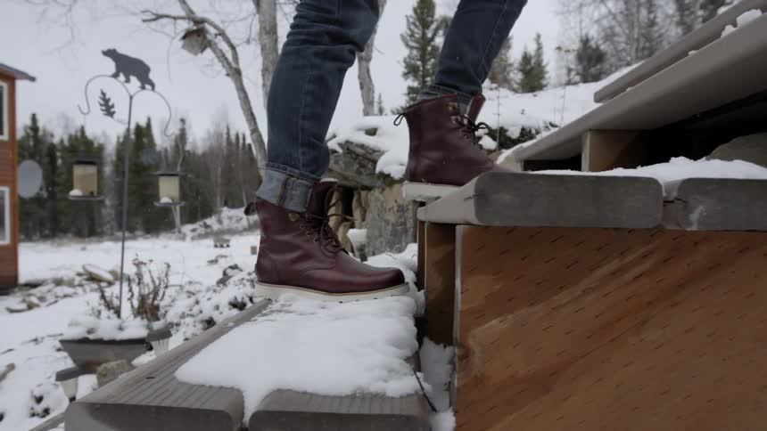 A man walks up snow covered wooden steps