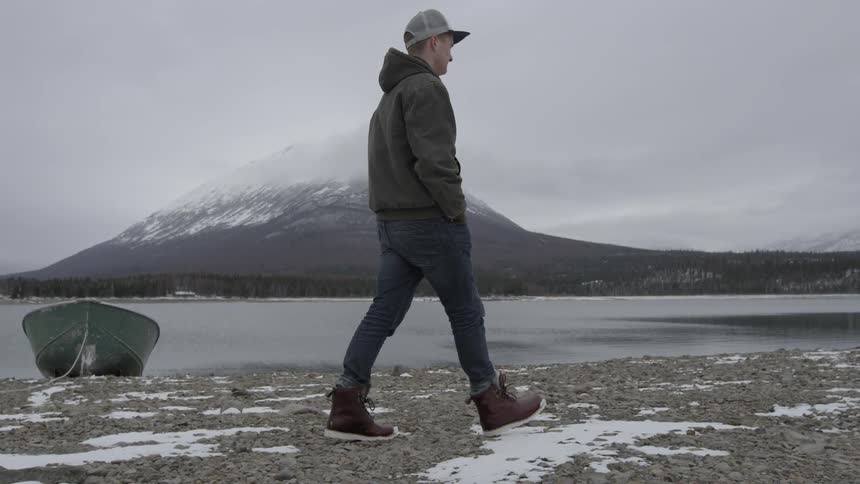 A man is walking along the coast on a cloudy day