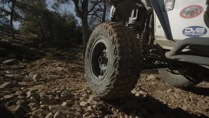 Jeep driving over rocky terrain in trees