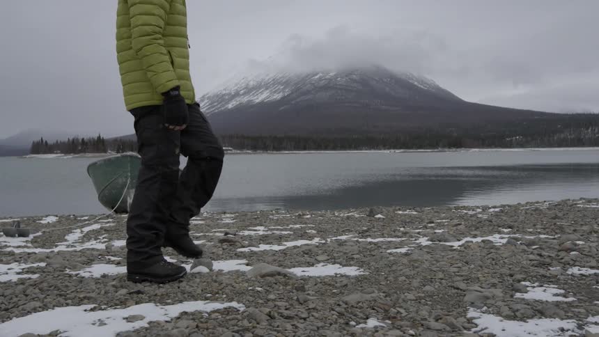 Person walking on a cold rocky beach on a cloudy day