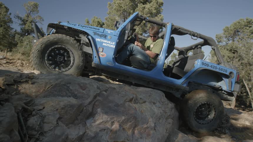 A man is trying to get over a rock in an off-road vehicle