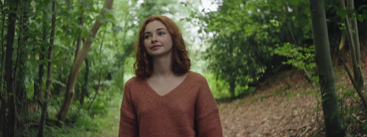 Young redheaded woman walking along a forest trail