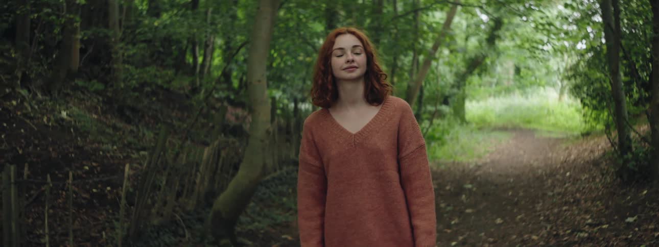 Woman in a brown blouse walking along a trail in the forest