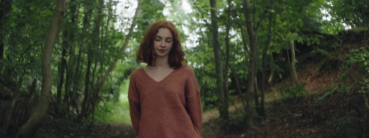 A woman is smiling in the forest