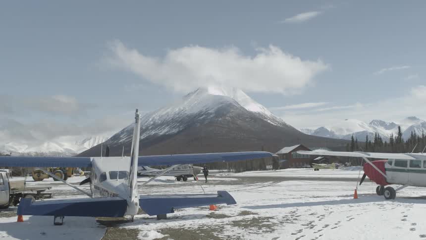 A man walking toward an airplane on a field that is covered with snow